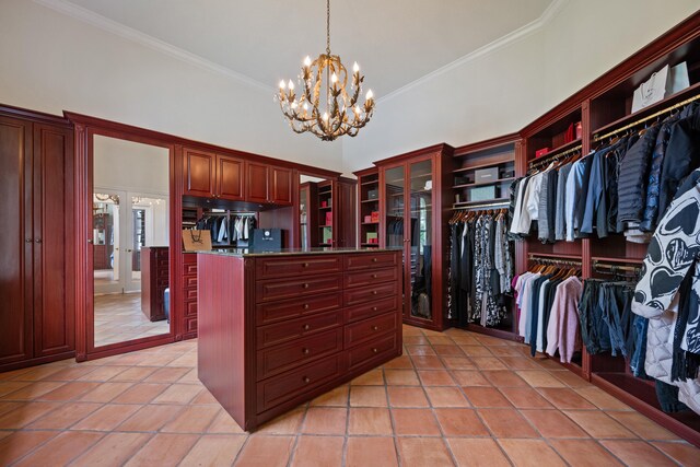 walk in closet with light tile patterned floors, a towering ceiling, and an inviting chandelier