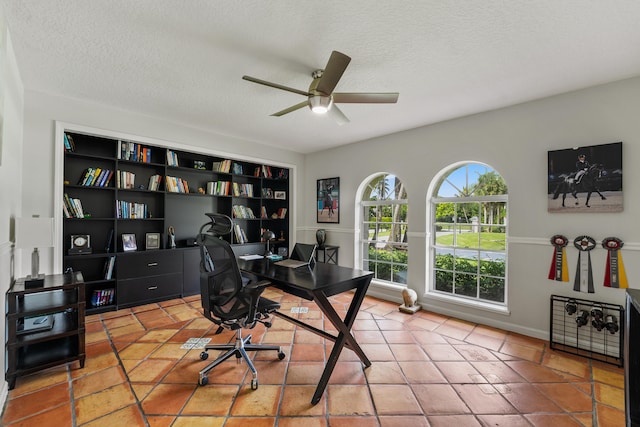 tiled office space featuring a textured ceiling and ceiling fan