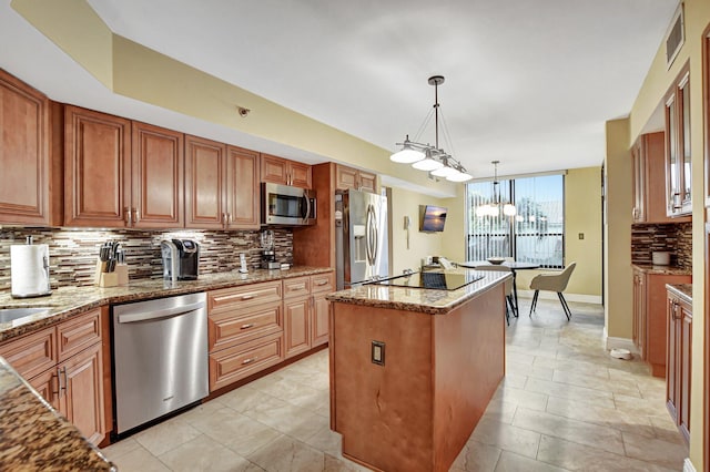 kitchen with tasteful backsplash, hanging light fixtures, light stone counters, a kitchen island, and stainless steel appliances