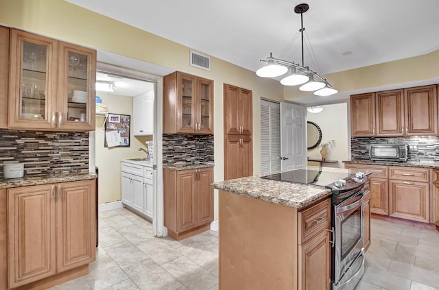 kitchen with decorative backsplash, a kitchen island, hanging light fixtures, electric range, and light stone counters