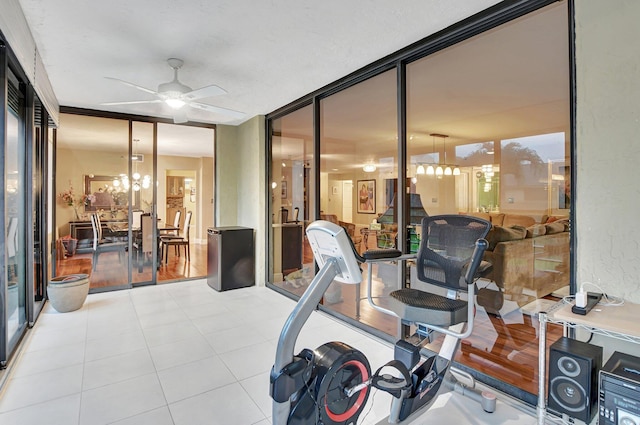 workout area with a wall of windows, ornamental molding, light hardwood / wood-style flooring, and ceiling fan with notable chandelier