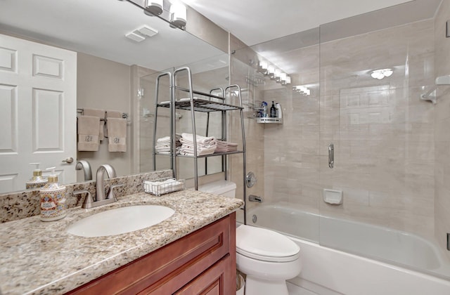 full bathroom featuring toilet, bath / shower combo with glass door, and vanity