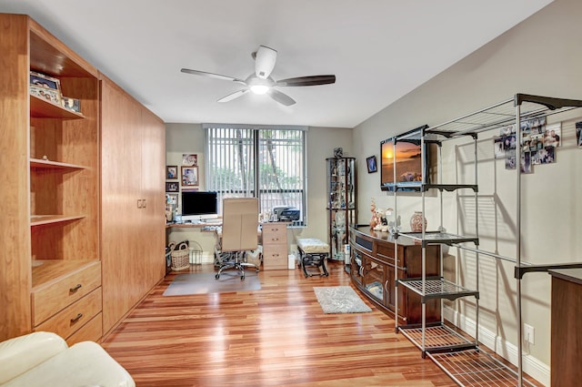 office featuring built in desk, light hardwood / wood-style floors, and ceiling fan