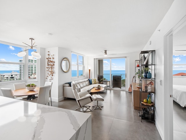 living room with plenty of natural light, a water view, and ceiling fan with notable chandelier