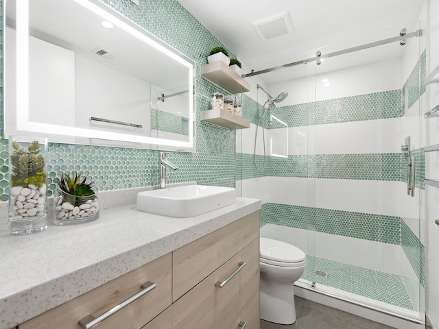 bathroom featuring vanity, a shower with door, tile patterned flooring, toilet, and tasteful backsplash