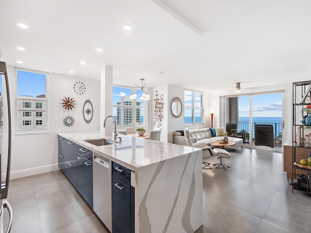 kitchen featuring stainless steel dishwasher, ceiling fan with notable chandelier, sink, pendant lighting, and a water view