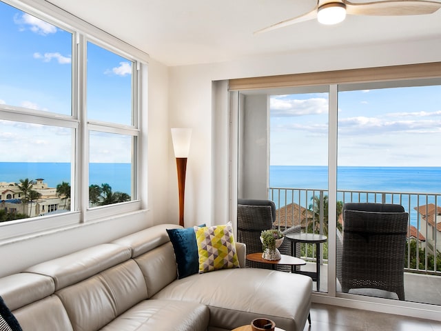 living room with ceiling fan, a water view, and concrete flooring