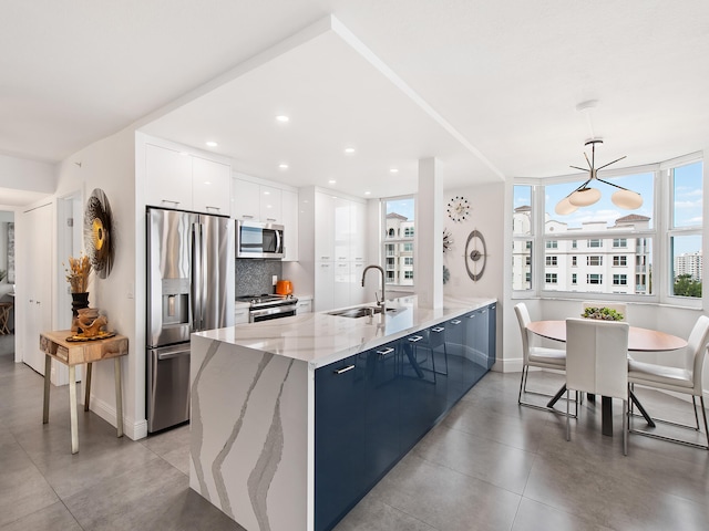 kitchen with white cabinetry, sink, stainless steel appliances, backsplash, and pendant lighting