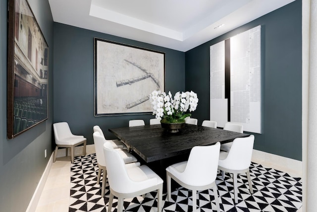 dining space with light tile patterned flooring and a tray ceiling