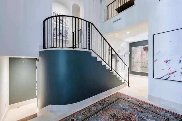 staircase with a towering ceiling and decorative columns