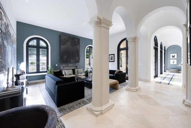 living room featuring french doors, ornate columns, and a towering ceiling