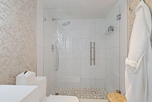 bathroom featuring a shower with door and toilet