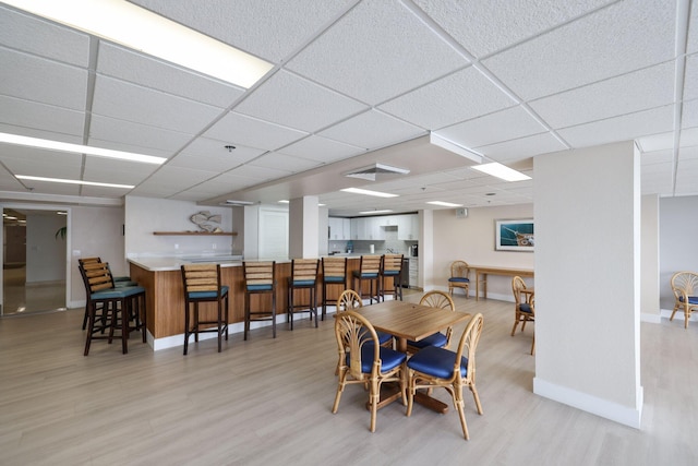 dining space featuring a drop ceiling and light wood-type flooring