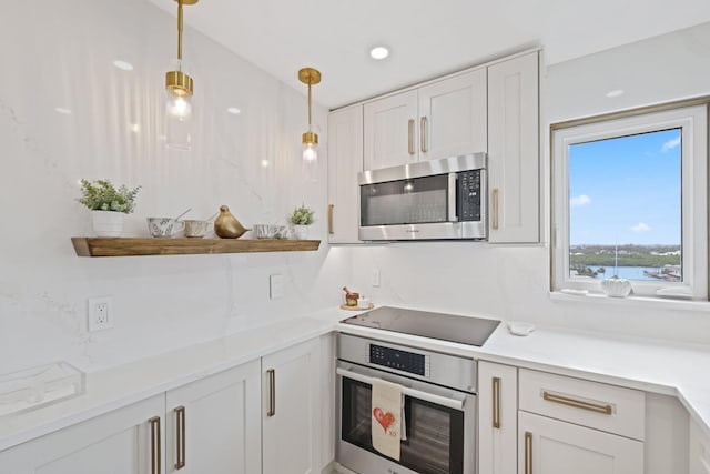 kitchen featuring decorative light fixtures, white cabinetry, appliances with stainless steel finishes, light stone counters, and tasteful backsplash