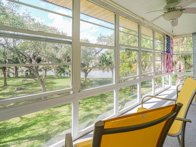 unfurnished sunroom with a ceiling fan and a water view