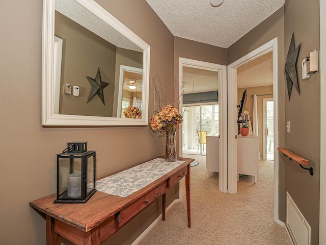 hall featuring a textured ceiling and light colored carpet