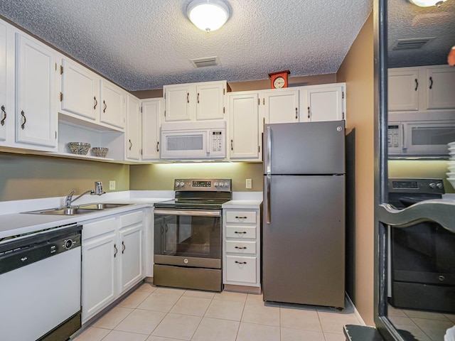 kitchen featuring light tile patterned floors, visible vents, appliances with stainless steel finishes, white cabinetry, and a sink