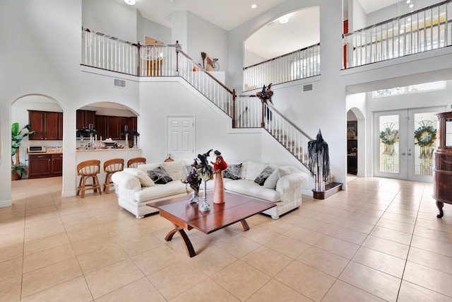 living room featuring french doors, light tile patterned flooring, and a high ceiling