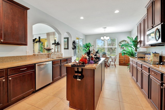 kitchen with sink, a kitchen island, stainless steel appliances, a notable chandelier, and light tile patterned floors