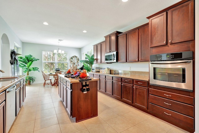 kitchen featuring hanging light fixtures, stainless steel appliances, sink, a center island, and an inviting chandelier