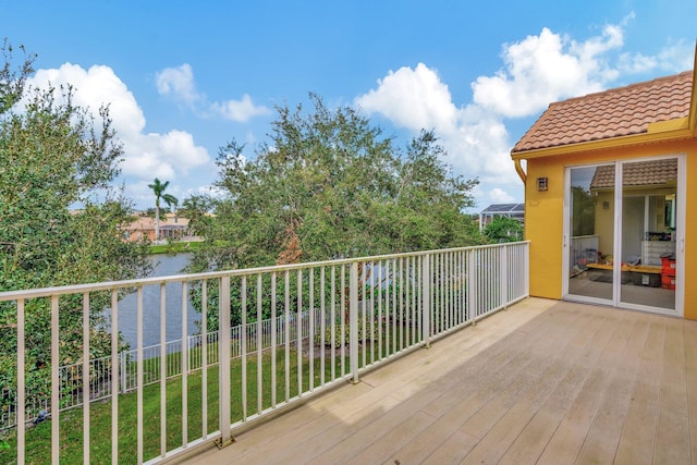 wooden deck with a water view and a lawn