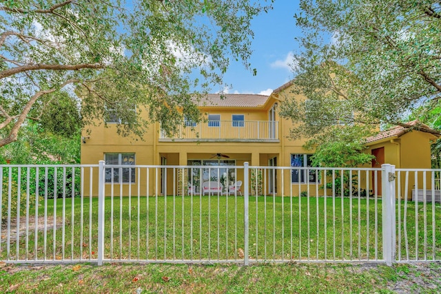 back of property with ceiling fan, a lawn, and a balcony