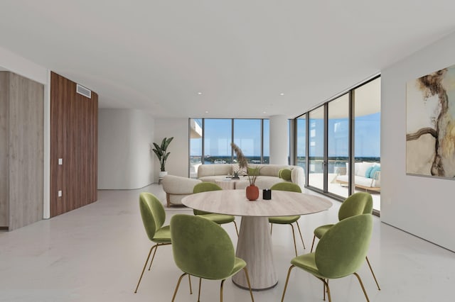 dining room featuring a water view and a wall of windows