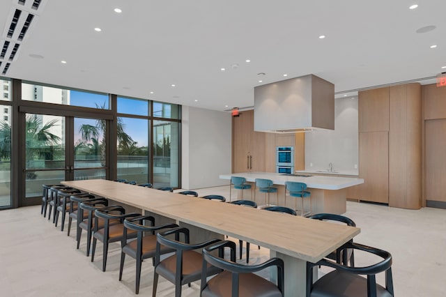 kitchen featuring a large island, french doors, a wall of windows, double oven, and a breakfast bar