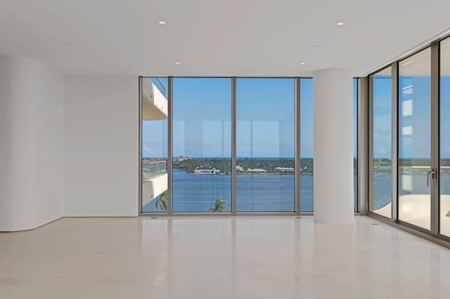 tiled spare room featuring a water view, expansive windows, and a healthy amount of sunlight