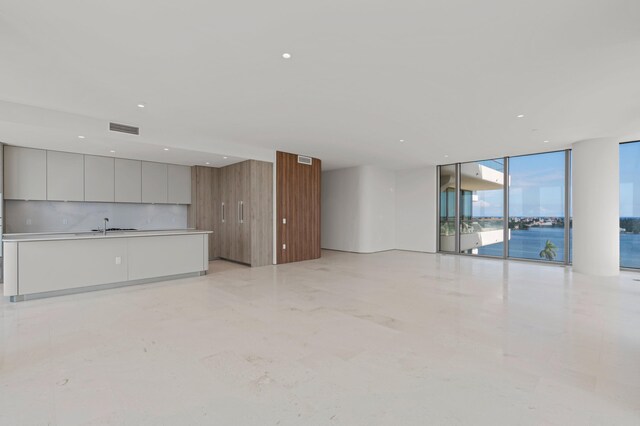 unfurnished living room with a water view, floor to ceiling windows, and sink