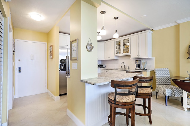 kitchen with light stone counters, a sink, stainless steel fridge with ice dispenser, tasteful backsplash, and glass insert cabinets