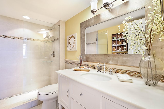 full bath featuring tiled shower, vanity, toilet, and tile walls