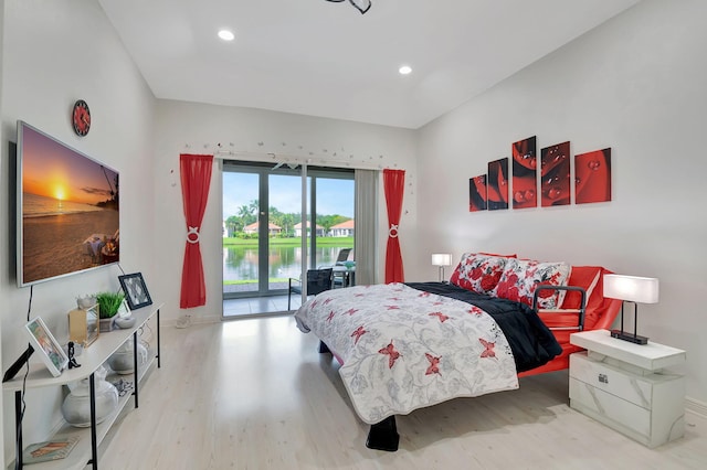 bedroom with access to exterior, a water view, and light hardwood / wood-style floors