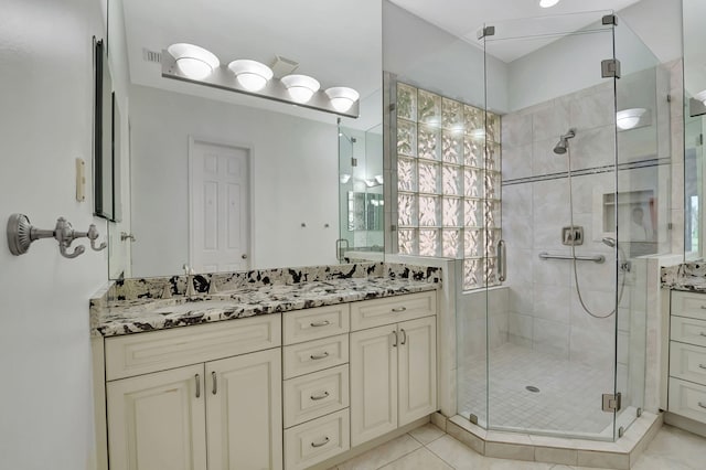 bathroom featuring a shower with door, vanity, and tile patterned floors