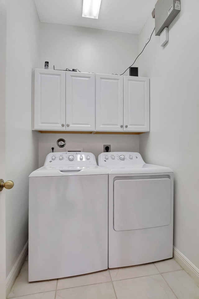 laundry room featuring independent washer and dryer, light tile patterned floors, and cabinets