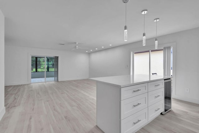 empty room featuring ceiling fan, light wood-type flooring, and beverage cooler