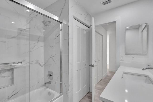 bathroom with vanity, enclosed tub / shower combo, and wood-type flooring