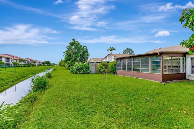 view of yard featuring a water view and a sunroom