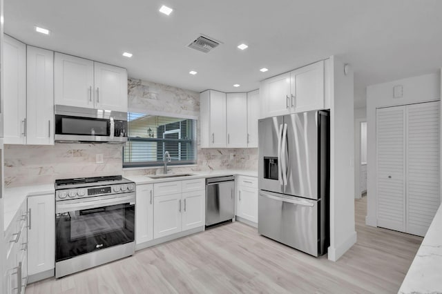 kitchen featuring sink, appliances with stainless steel finishes, light hardwood / wood-style flooring, and white cabinets