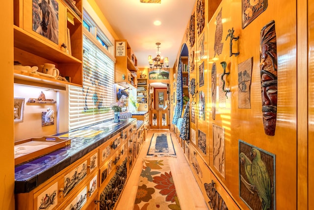 hall with light tile patterned floors and an inviting chandelier