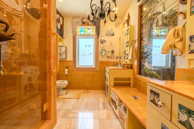 bathroom with tile walls, a wealth of natural light, vanity, and toilet