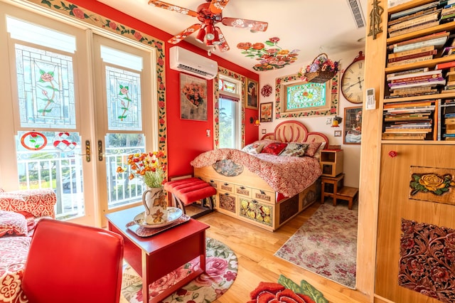 bedroom featuring multiple windows, a wall unit AC, hardwood / wood-style flooring, and ceiling fan