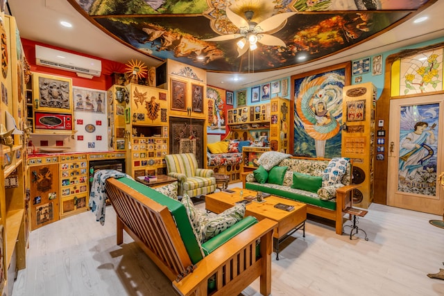 sitting room with a wall mounted AC, wood-type flooring, and ceiling fan