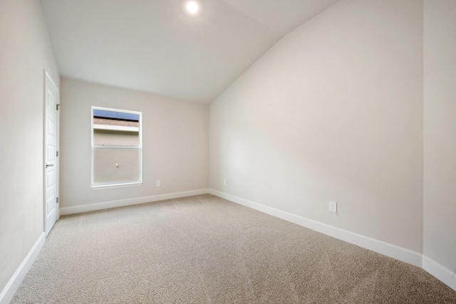 spare room featuring carpet floors and vaulted ceiling