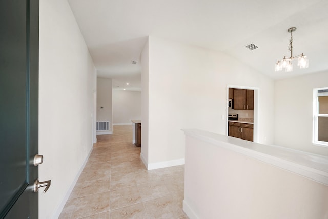 corridor featuring an inviting chandelier, lofted ceiling, and light tile patterned flooring