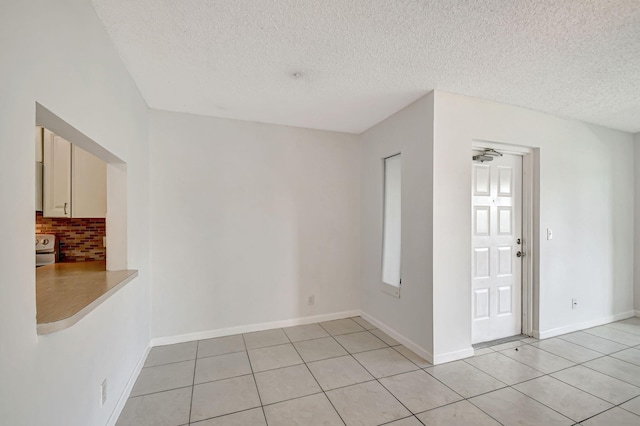 unfurnished room with a textured ceiling, ceiling fan, and light tile patterned floors