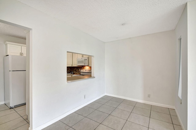 tiled spare room featuring a textured ceiling