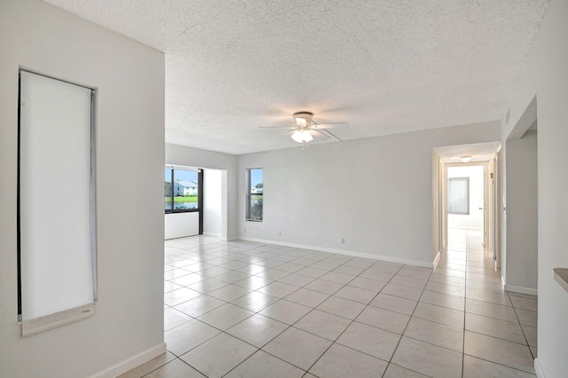 spare room with a textured ceiling, light tile patterned floors, and ceiling fan