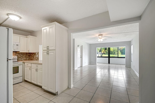 kitchen with white appliances, white cabinetry, and light tile patterned flooring