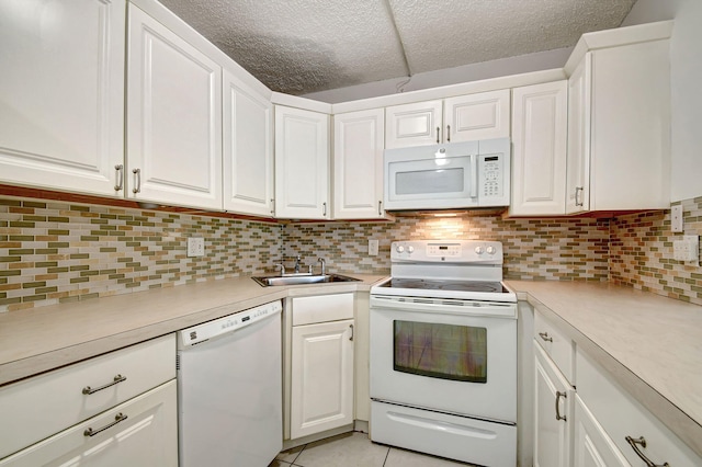 kitchen with white appliances, a textured ceiling, light tile patterned floors, and white cabinets